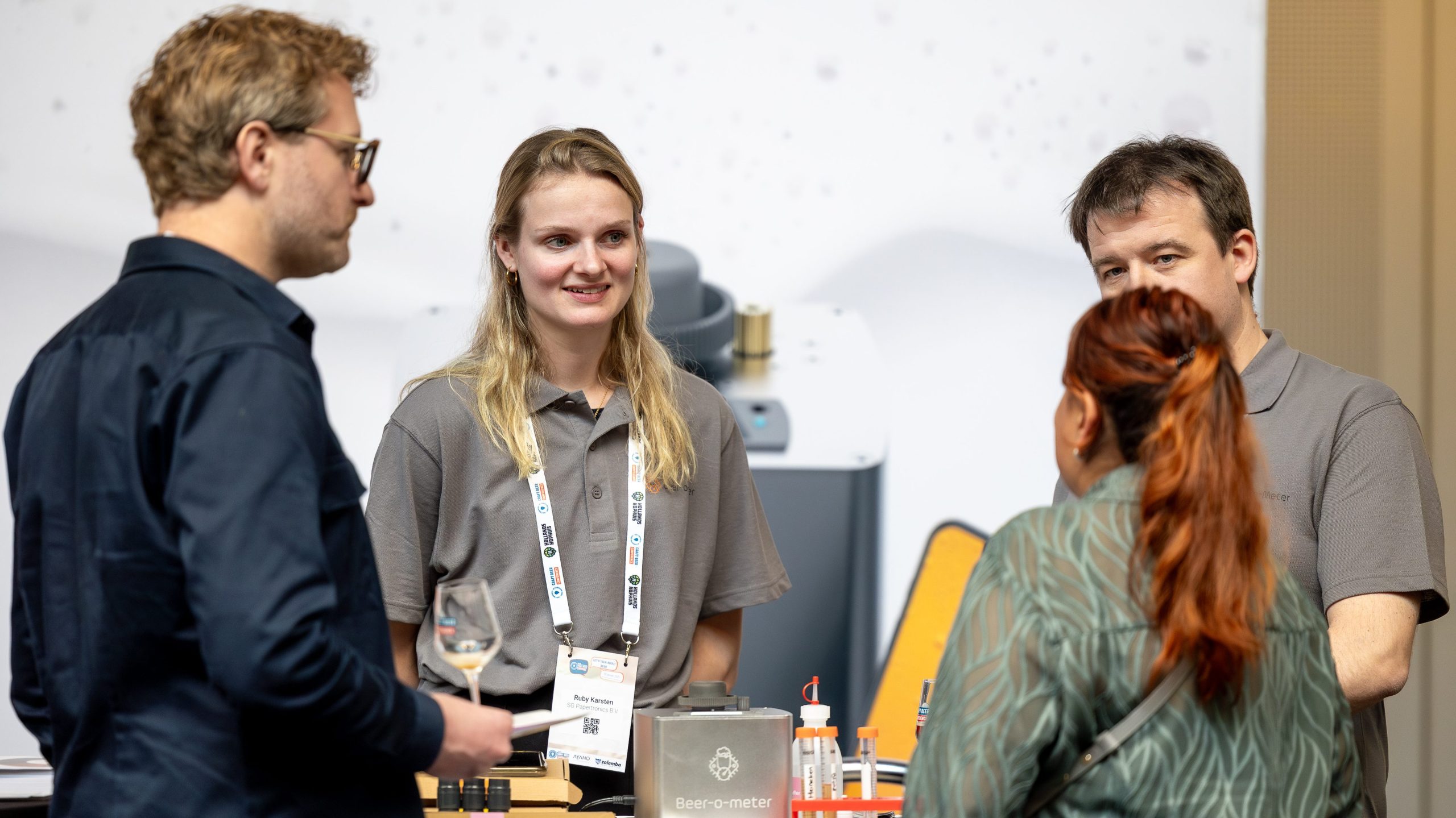 Beer-o-Meter team talking with visitors at a conference booth, demonstrating quality control tools and beer testing equipment